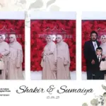 Guests wearing props in front of a red photo booth backdrop